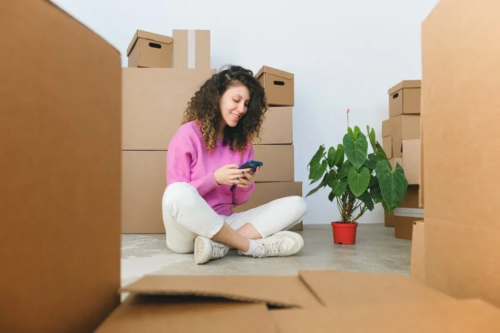 A girl sitting around boxes in a pink top looking for rental property management software