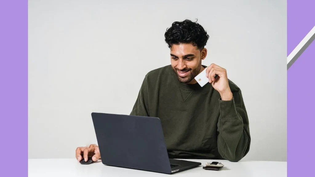 Man sitting in front of laptop and working it with holding his credit card
